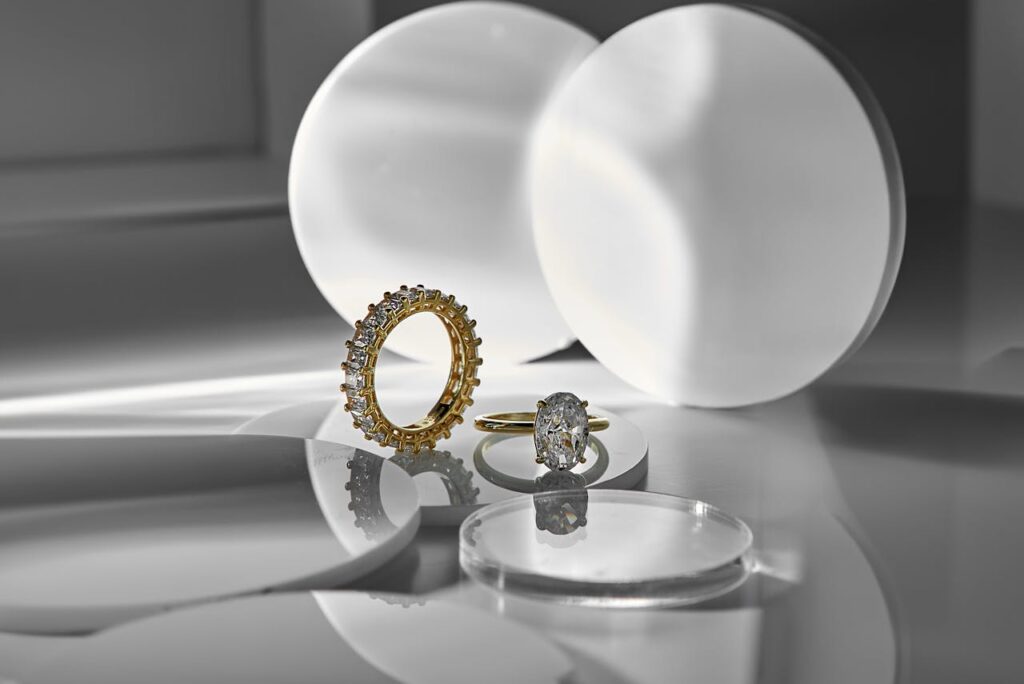 Elegant diamond and gold rings on a reflective surface in a minimalist setting, showcasing luxury and sophistication.